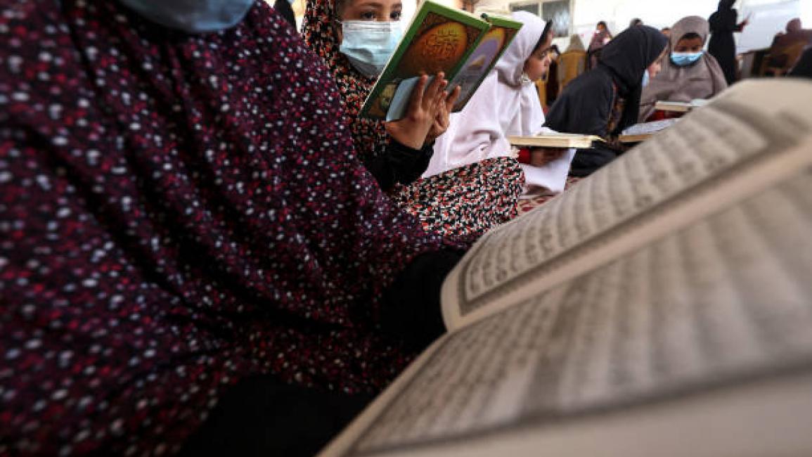 	Young Palestinian girls wearing face masks due to the coronavirus pandemic, read the Koran during the Muslim holy month of Ramadan, in Gaza City, on April 15, 2021. (Photo by MOHAMMED ABED / AFP) (Photo by MOHAMMED ABED/AFP via Getty Images)