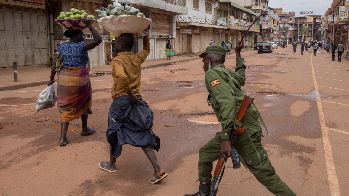 TOPSHOT-UGANDA-HEALTH-VIRUS TOPSHOT - A police officer beats a female orange vendor on a street in Kampala, Uganda, on March 26, 2020, after Ugandan President Yoweri Museveni directed the public to stay home for 32 days starting March 22, 2020 to curb the spread of the COVID-19 coronavirus. - Ugandan authorities have identified 14 confirmed cases of the COVID-19 coronavirus in the country. All borders have been closed except for limited goods and authorised emergency flights. (Photo by Badru KATUMBA / AFP) 