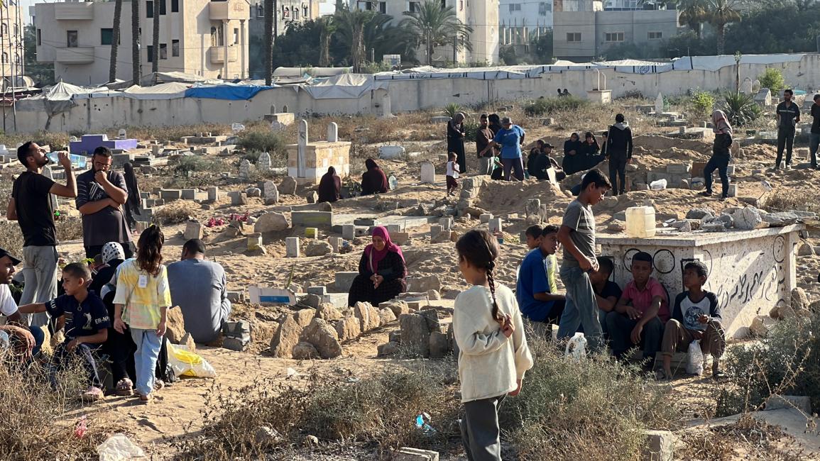 غزيون يزورون قبور أقارب راحوا ضحية غارات جيش الاحتلال الإسرائيلي (أنس زياد فتيحة/الاناضول)