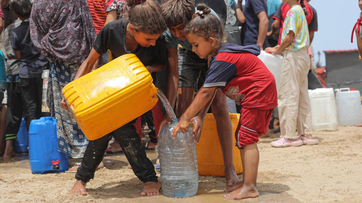 ينتظر الأطفال في طوابير طويلة للحصول على الماء (حسن جدي/الأناضول)